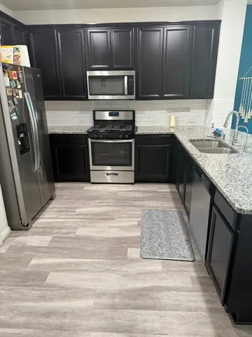 a kitchen with stainless steel appliances granite countertop a stove microwave and refrigerator