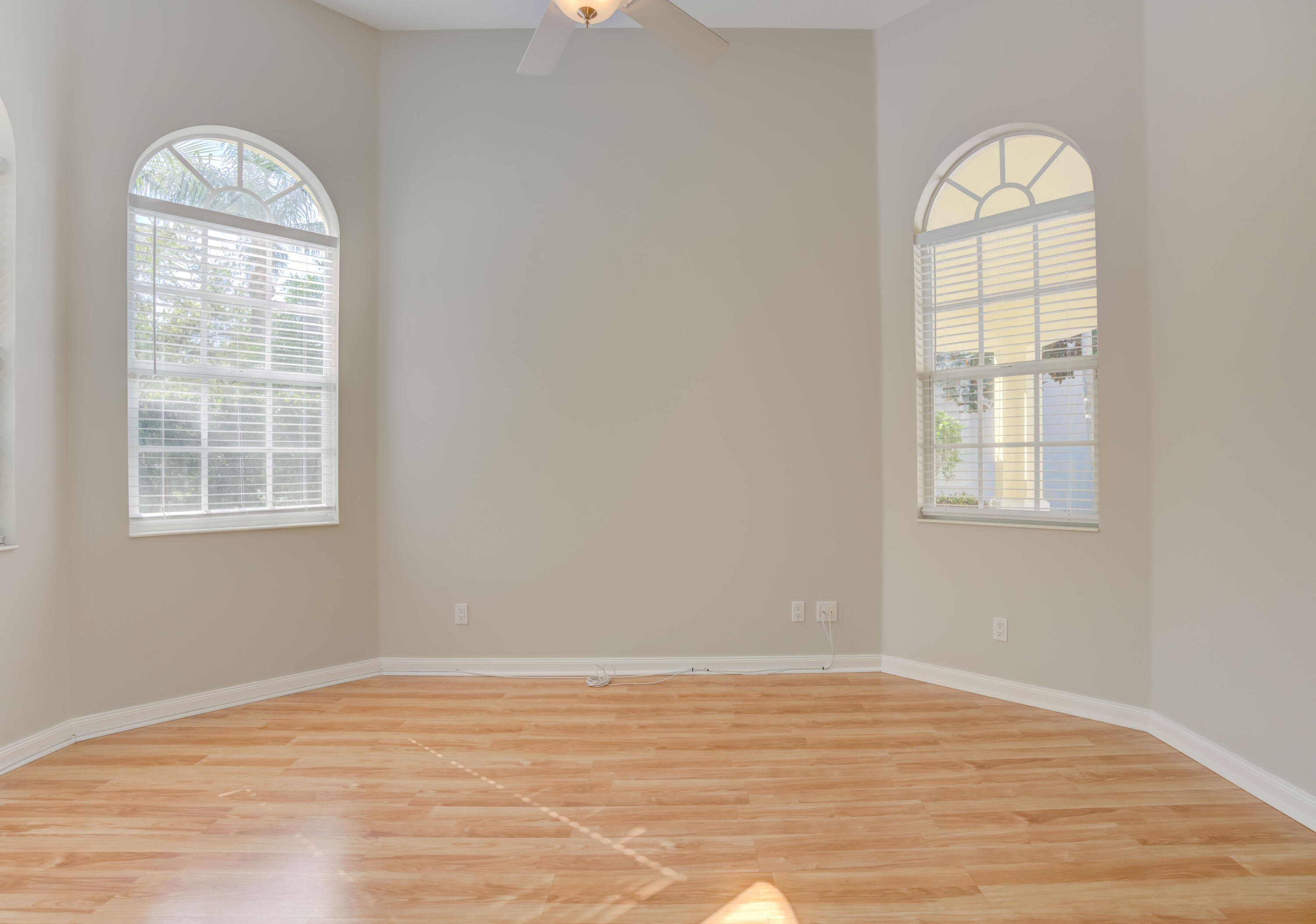 256 San Remo Drive Jupiter, FL 33458 - Photo 17 of 46 an empty room with wooden floor chandelier fan and windows