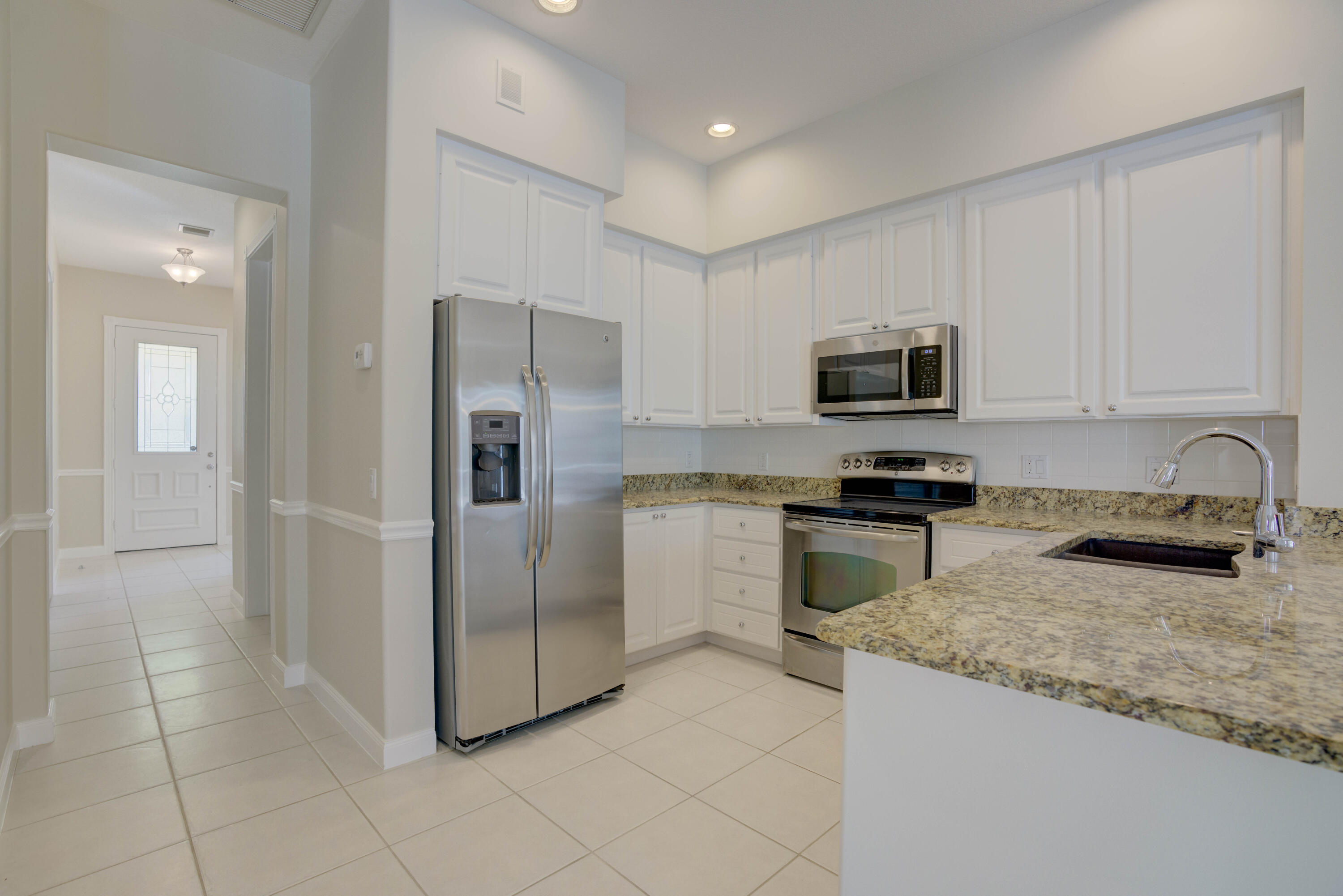 256 San Remo Drive Jupiter, FL 33458 - Photo 2 of 46 a kitchen with granite countertop a refrigerator and a stove top oven