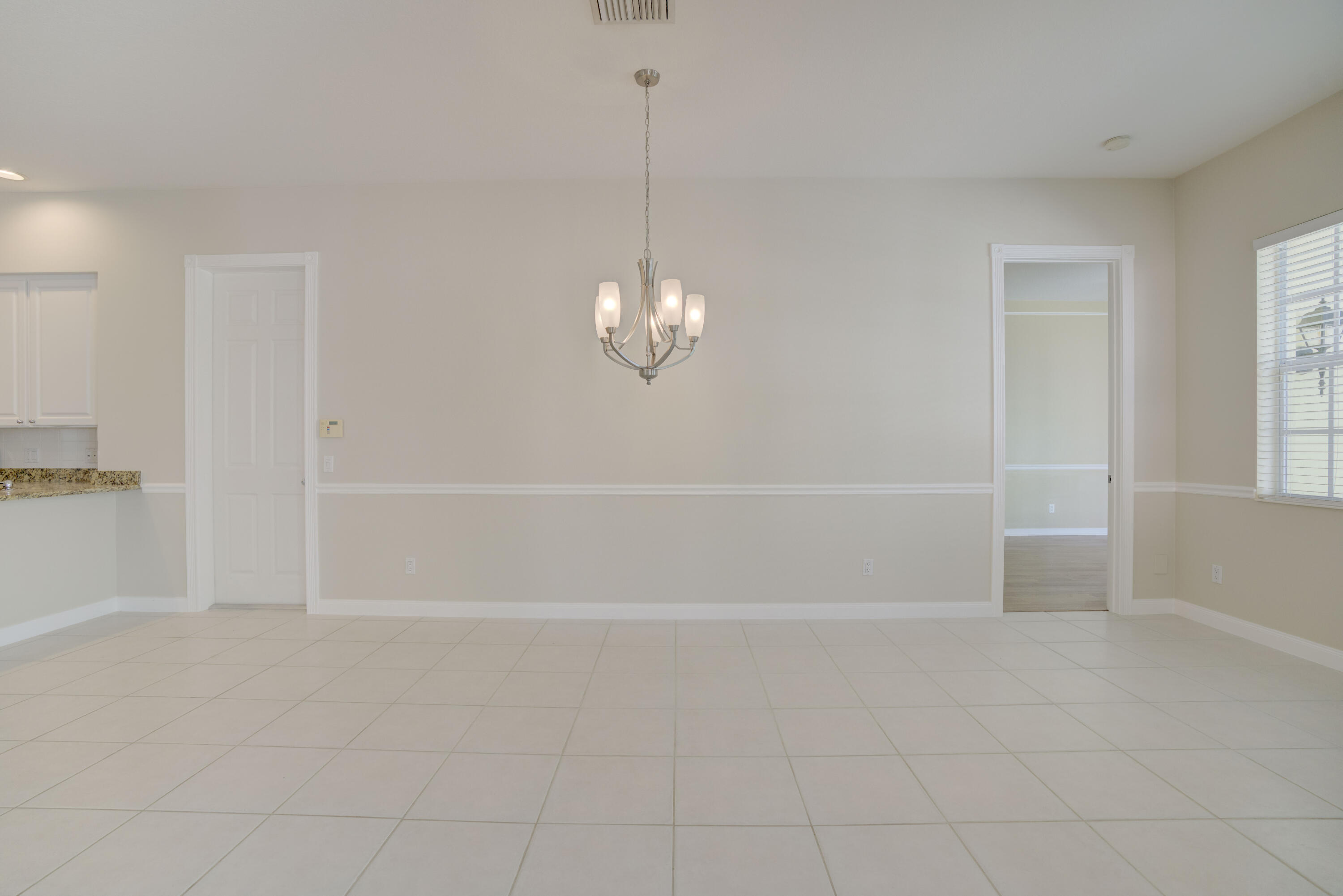 256 San Remo Drive Jupiter, FL 33458 - Photo 34 of 46 a view of an empty room with chandelier fan and kitchen view
