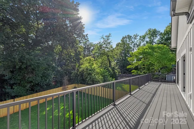 a balcony with wooden floor and trees in the background