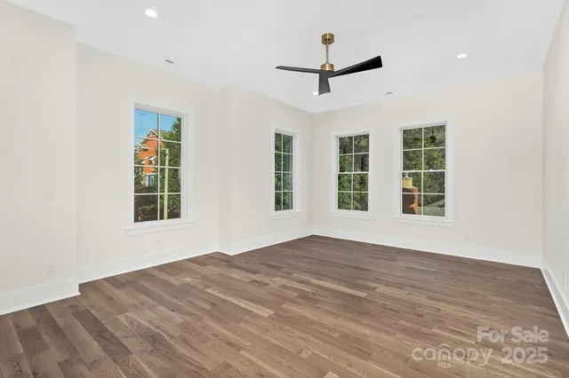 a view of an empty room with a window and wooden floor