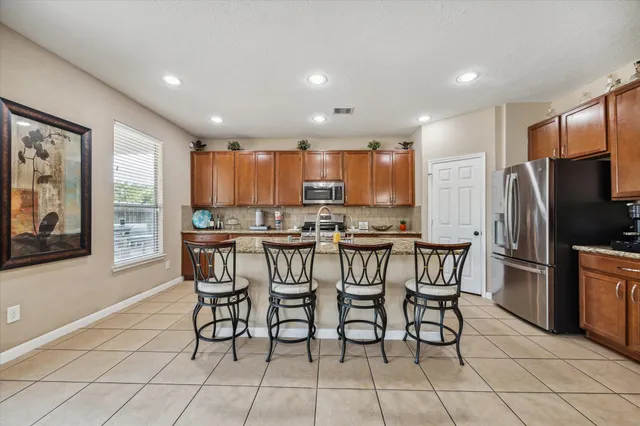 a kitchen with stainless steel appliances a dining table chairs refrigerator and microwave