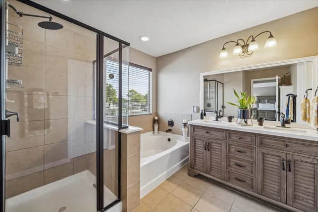 a spacious bathroom with a double vanity sink a large mirror a bathtub and next to a window
