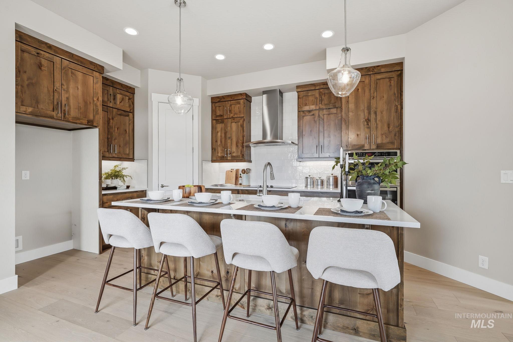 470 South Radiator Way Boise, ID 83716 - Photo 21 of 50 Gourmet kitchen featuring a substantial island with seating, natural wood cabinetry, light wood-finish flooring, recessed lighting, and stylish pendant fixtures