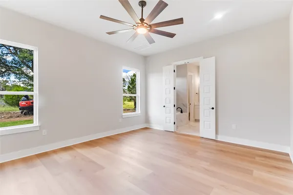 an empty room with windows and a ceiling fan