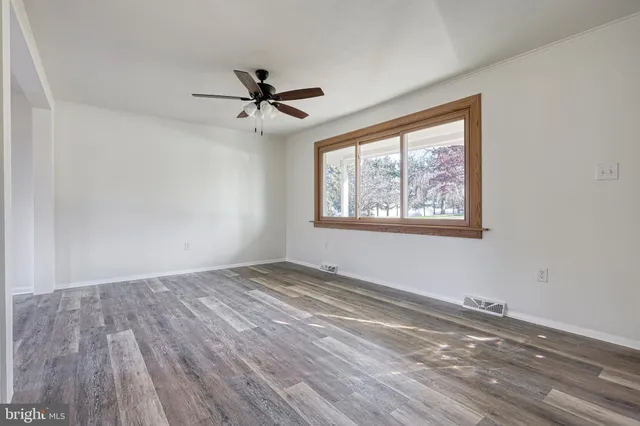 a view of empty room with window and ceiling fan
