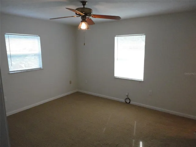 an empty room with a window and a fan