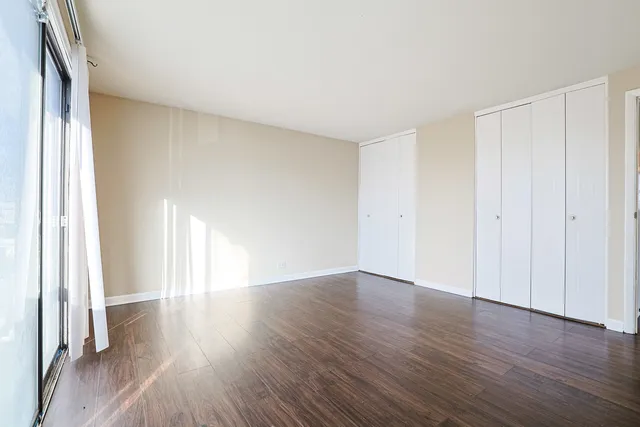 a view of an empty room with wooden floor and a window