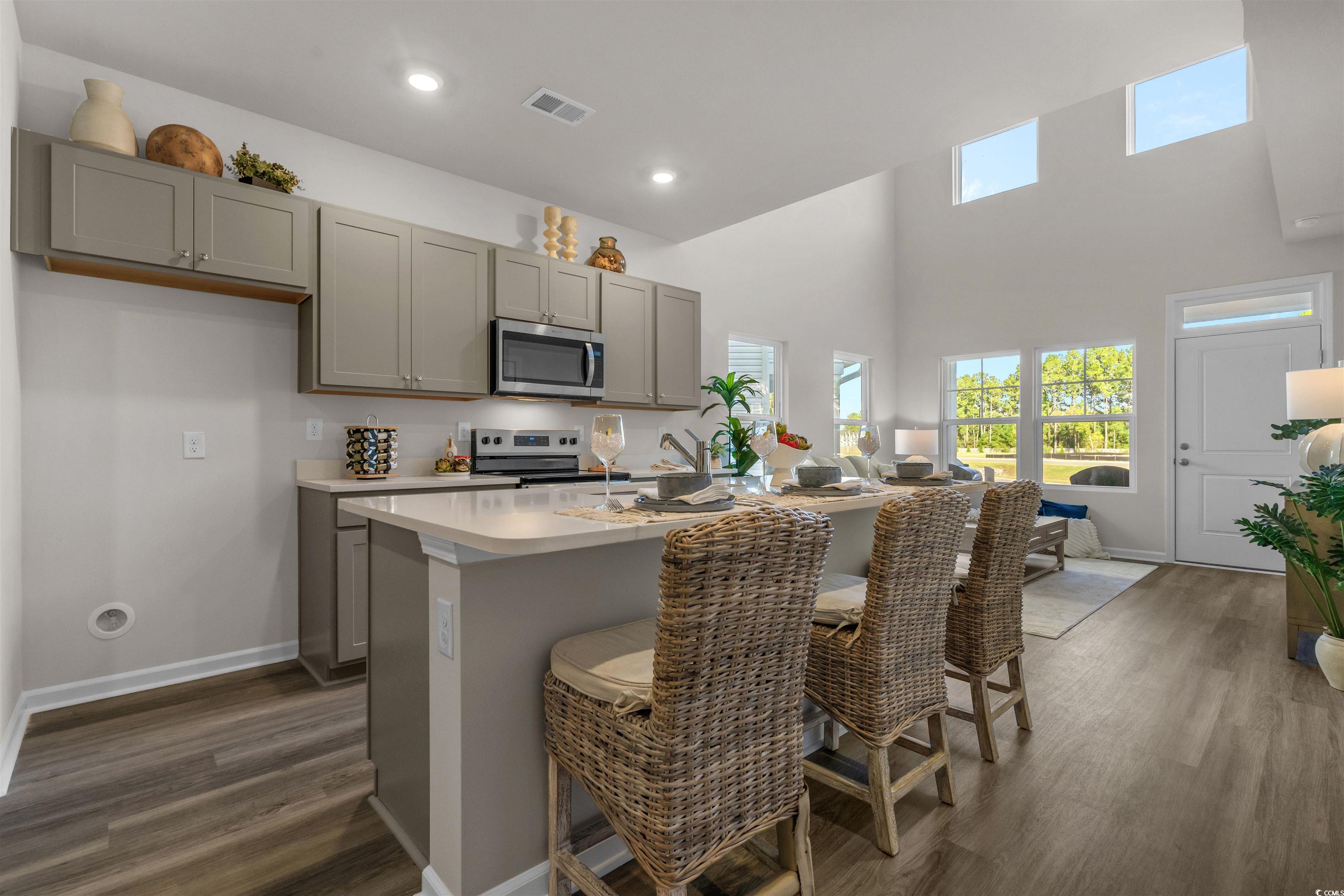 814 Palm Frond Way, Unit 42 Calabash, NC 28467 - Photo 19 of 31 Kitchen with gray cabinetry, dark wood-style flooring, an island with sink, a towering ceiling, and recessed lighting