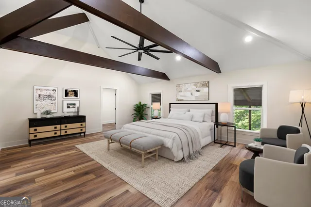 a spacious bedroom with a bed a couch and a flat tv screen on the dresser