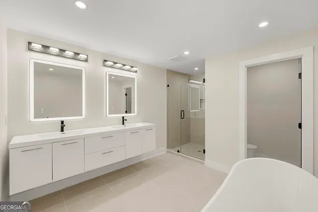 a spacious bathroom with a double vanity sink mirror and bathtub