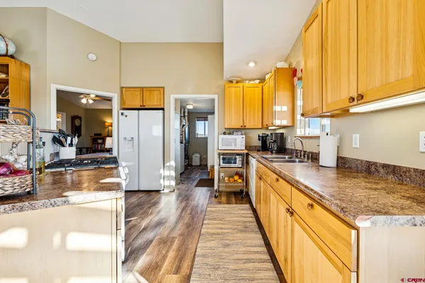 a kitchen with stainless steel appliances granite countertop a refrigerator a oven and white cabinets with wooden floors
