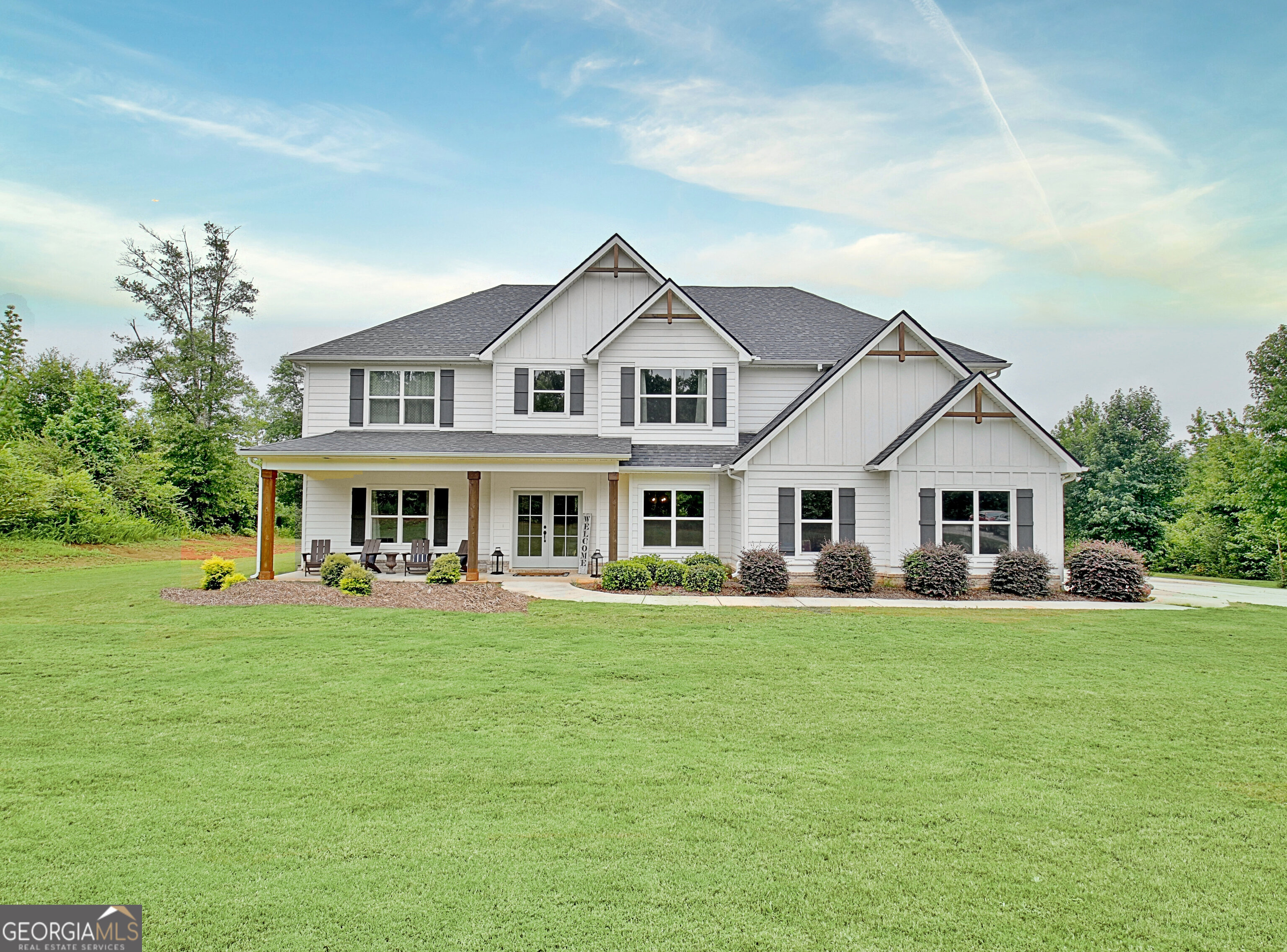 a front view of a house with a garden and trees