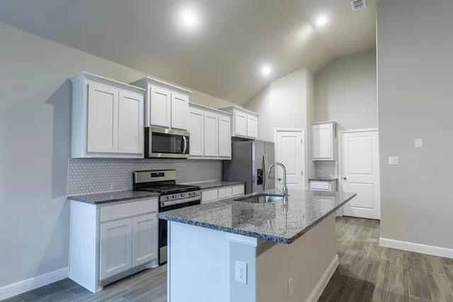 a kitchen with stainless steel appliances granite countertop a refrigerator a stove and a wooden floors