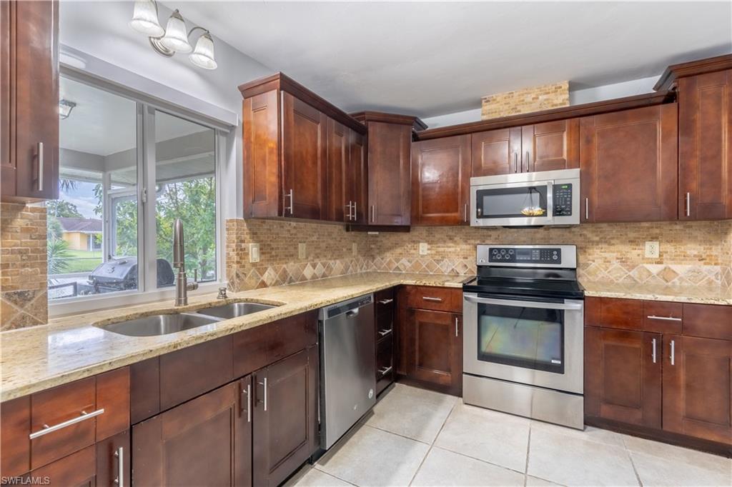 2100 55th Street Southwest Naples, FL 34116 - Photo 24 of 50 a kitchen with stainless steel appliances granite countertop a sink stove and microwave