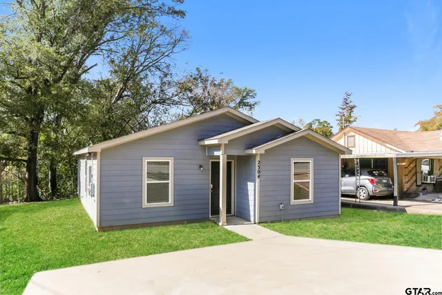a view of a yard in front of a house with a large tree