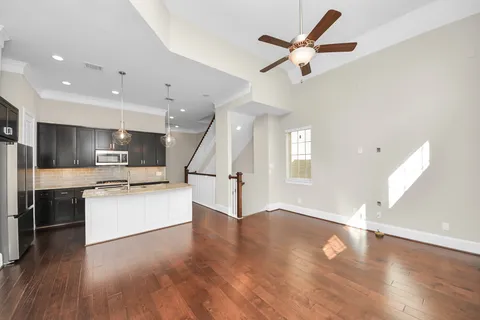 a large kitchen with stainless steel appliances kitchen island a large counter top and wooden floors