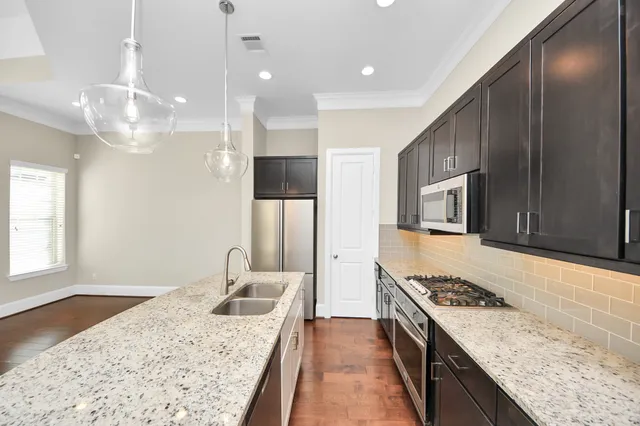 a large kitchen with stainless steel appliances kitchen island a large counter top and wooden floors