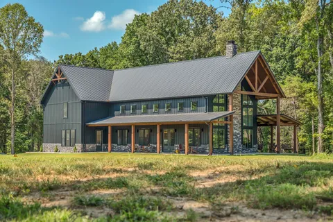 an aerial view of residential house with outdoor space and trees all around