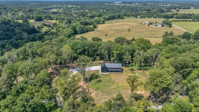 an aerial view of residential house with outdoor space and trees all around