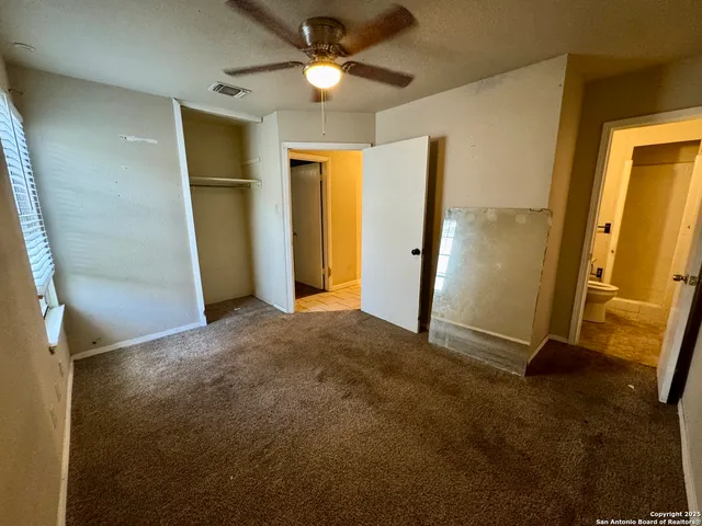 an empty room with closet and a ceiling fan