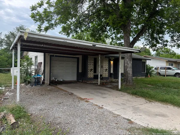 a view of a house with a yard plants and large tree
