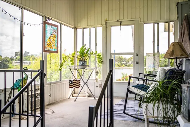 a view of a lake with lawn chairs and large trees