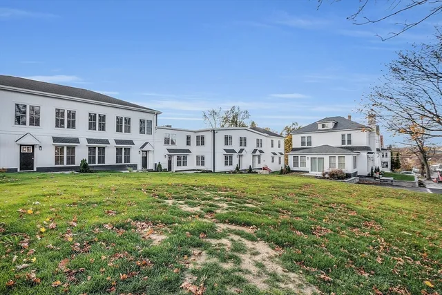 a view of a big house with a big yard and large trees