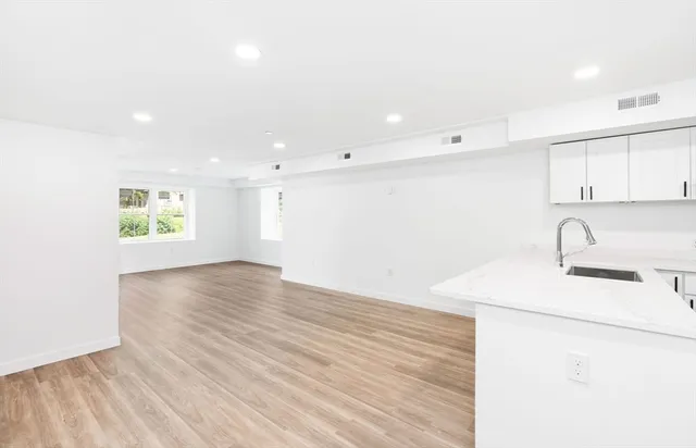 a view of a kitchen with a sink and dishwasher with wooden floor