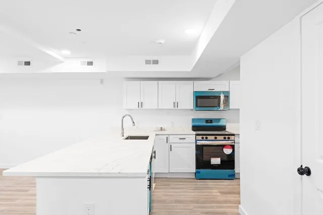 a kitchen with stainless steel appliances a refrigerator a stove and white cabinets