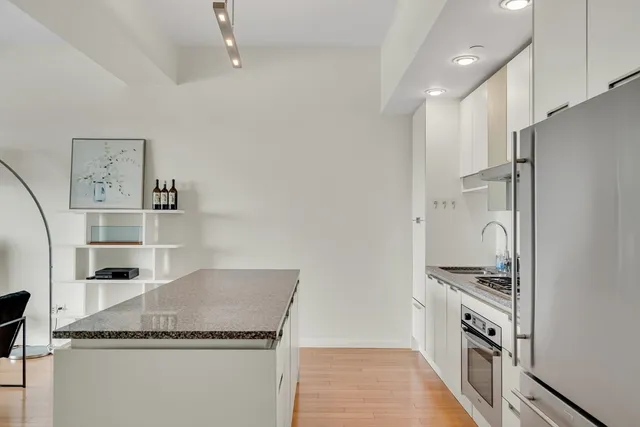 a kitchen with granite countertop a refrigerator and a stove top oven