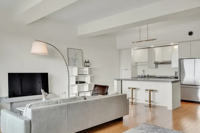 a living room with stainless steel appliances kitchen island granite countertop a couch and a stove top oven