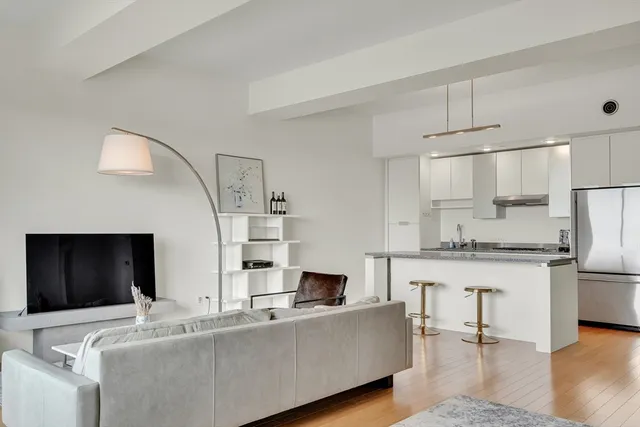 a living room with stainless steel appliances kitchen island granite countertop a couch and a stove top oven