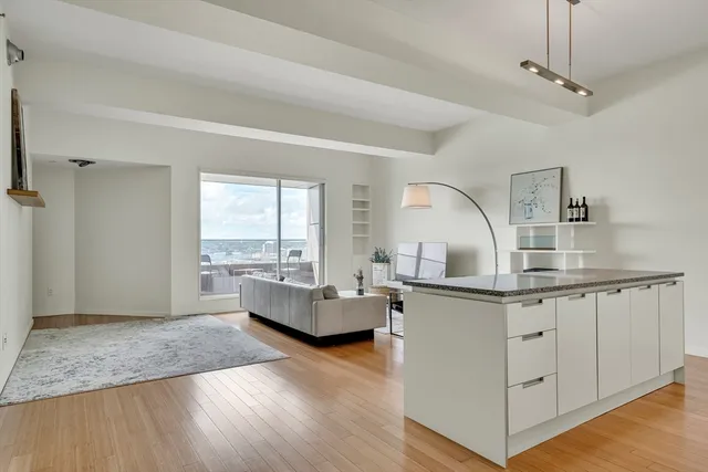 a kitchen with granite countertop a stove and white cabinets with wooden floor