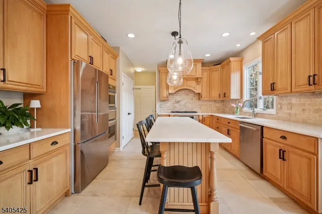 a kitchen with stainless steel appliances kitchen island granite countertop a stove top oven a sink dishwasher a dining table and chairs with wooden floor