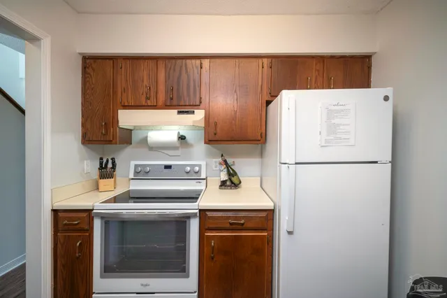 a white refrigerator freezer and a stove sitting inside of a kitchen