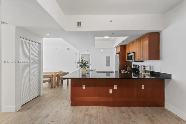 a large kitchen with stainless steel appliances a large counter top and a wooden floors