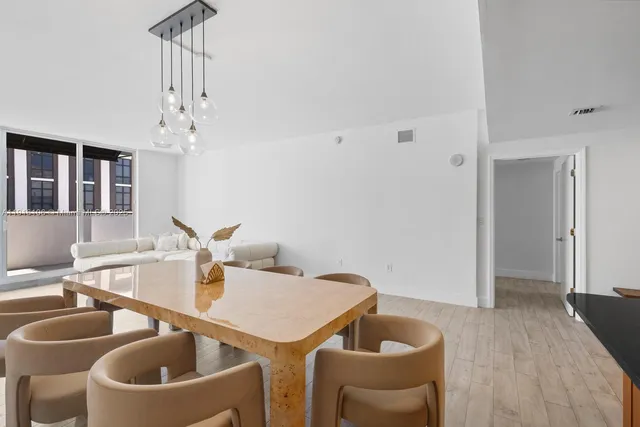 a kitchen with stainless steel appliances granite countertop a stove top oven a sink a dining table and chairs with wooden floor