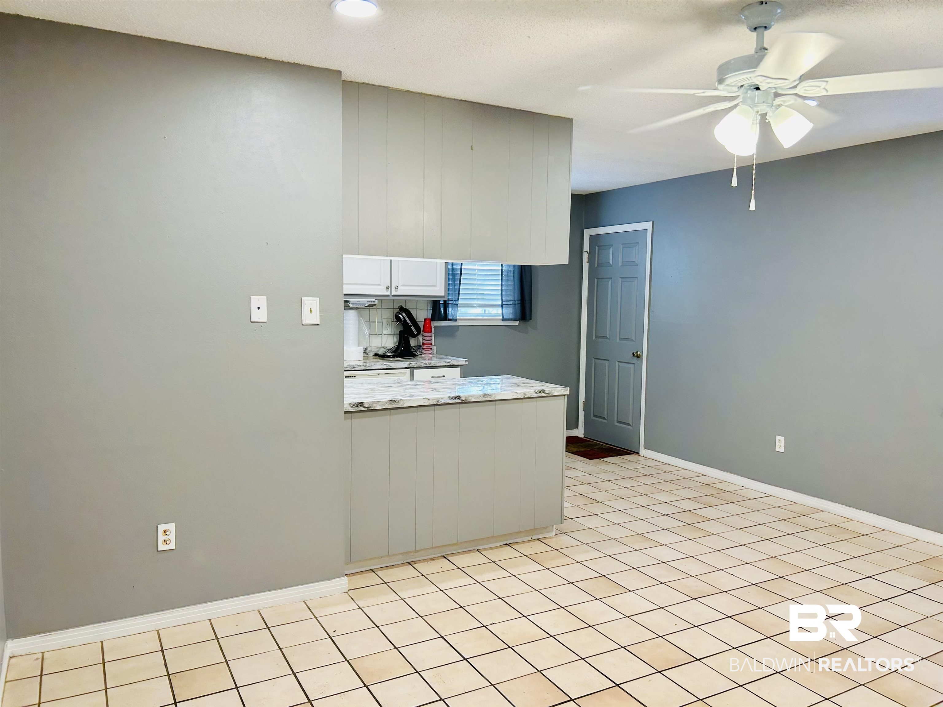 5925 Dixie Lane Mobile, AL 36693 - Photo 14 of 19 Kitchen featuring white cabinetry, backsplash, light tile patterned floors, ceiling fan, and light stone countertops