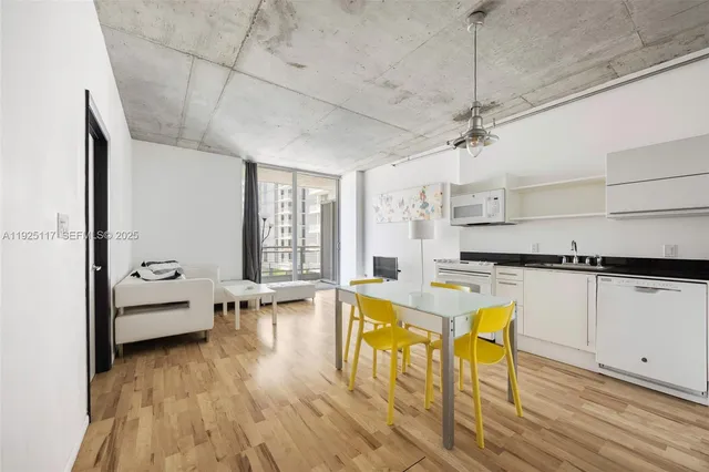 a living room with stainless steel appliances granite countertop furniture wooden floor and a view of kitchen