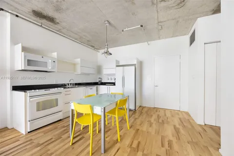 a kitchen with stainless steel appliances kitchen island granite countertop a table chairs refrigerator and microwave