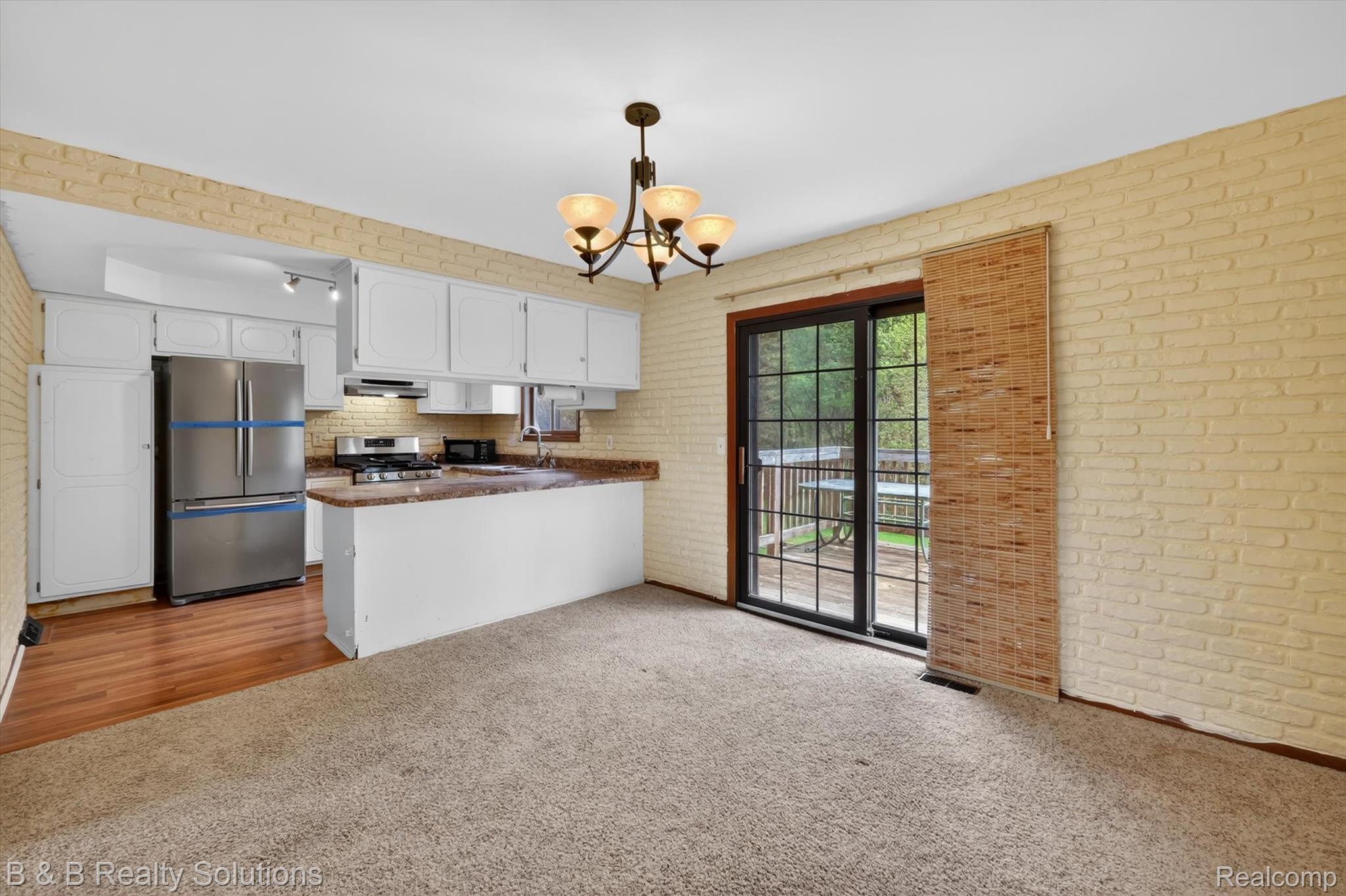 2467 North Lake George Road Metamora, MI 48455 - Photo 10 of 46 Kitchen with dark countertops, stainless steel appliances, white cabinets, suspended lighting, and light colored carpet