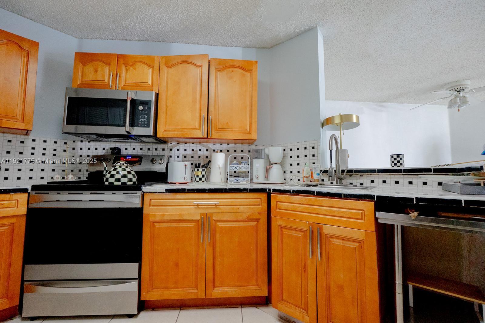 6276 Northwest 186th Street, Unit 112 Hialeah, FL 33015 - Photo 19 of 22 a kitchen with stainless steel appliances a stove sink and microwave
