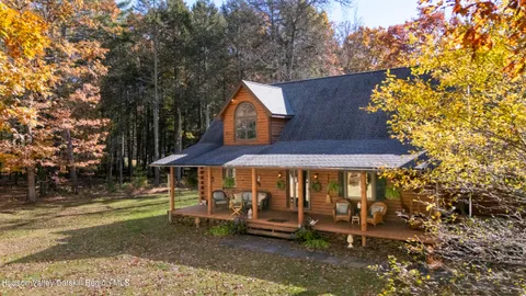 a view of patio with chairs and table under an umbrella with large trees