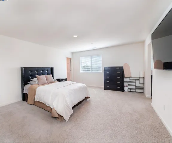 a spacious bedroom with a bed and dresser