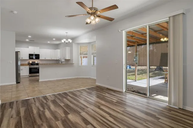 a view of kitchen and empty room with wooden floor