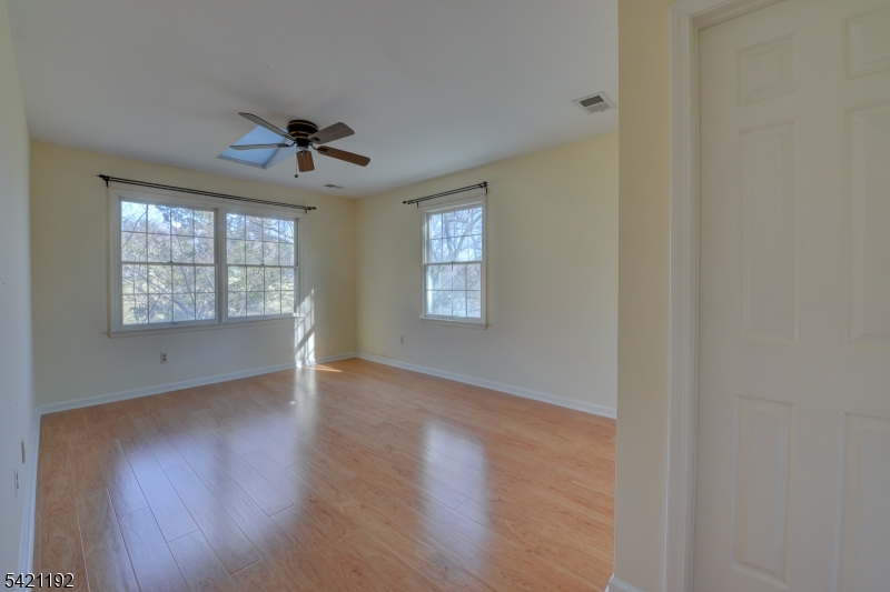 220 Alexandria Way Bernards, NJ 07920 - Photo 6 of 18 an empty room with wooden floor chandelier fan and windows
