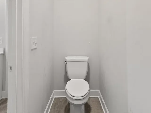 a white toilet sitting in a bathroom next to a wooden wall