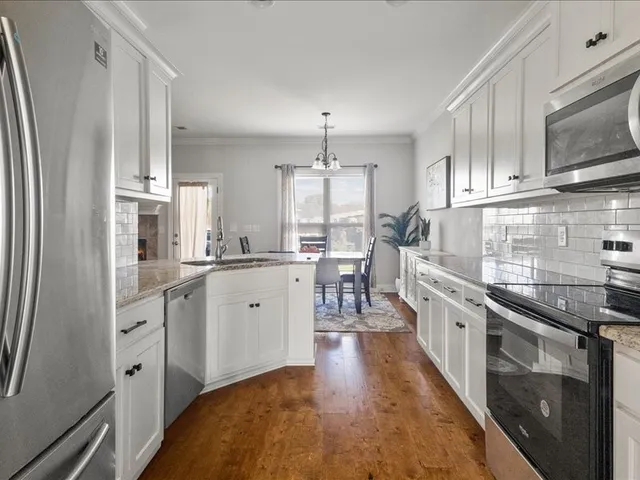 a kitchen with stainless steel appliances a refrigerator sink and white cabinets